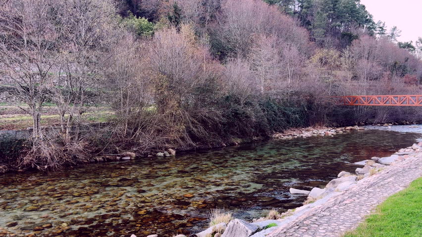 Shallow river flowing beside footbridge in Parque Lobios Spain