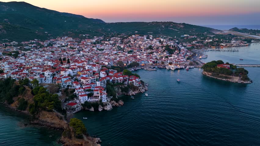 Panoramic summer evening aerial view of the illuminated town of Skiathos island, Sporades, Greece, with old port, Bourtzi island and new port in the background