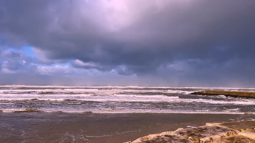 Dark storm clouds over the sea lightened by a rainbow.