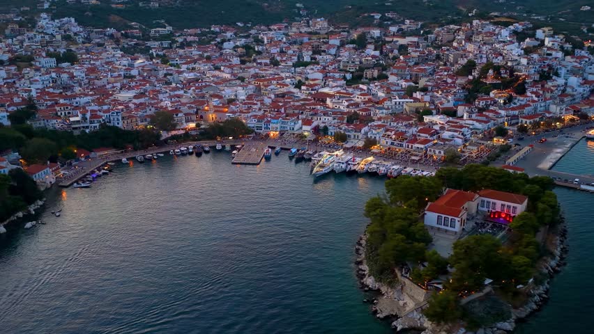 Panoramic summer evening aerial view of the illuminated town of Skiathos island, Sporades, Greece, with old port, Bourtzi island and new port in the background