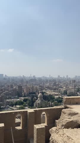 From a sweeping panoramic viewpoint, the city of Cairo stretches out in a vast mosaic of rooftops, streets, and distant hills, the urban landscape bathed in soft light. Rising majestically above it all, the Muhammad Ali Mosque dominates the scene, its elegant domes and towering minarets standing as a symbol of Cairo’s rich history and Islamic heritage. The contrast between the sprawling city and the mosque’s grand Ottoman-style architecture emphasizes both the scale and the serenity of this iconic landmark. The view captures the harmony of urban life and spiritual grandeur, offering a breathtaking perspective of one of Egypt’s most revered sites.