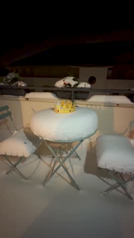 A golden paper crown rests on a snow covered outdoor table at night, symbolizing winter celebration and festive tradition.