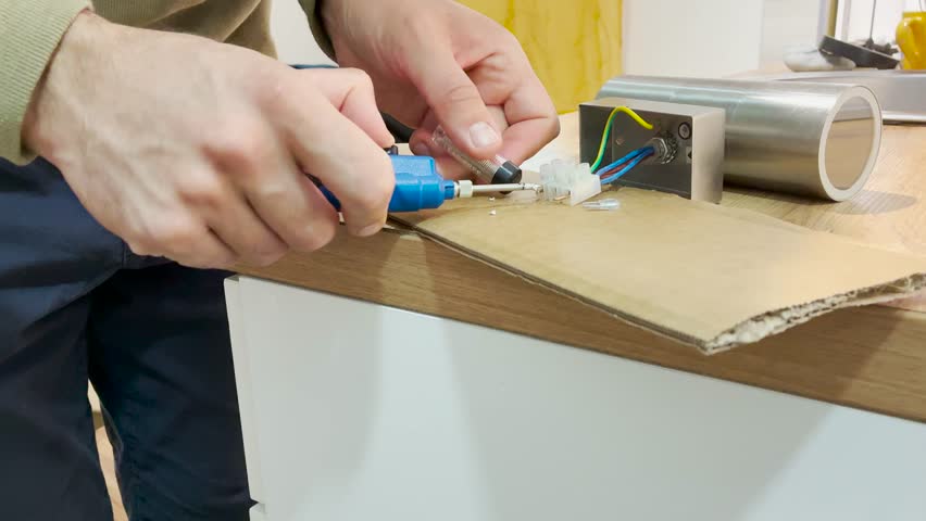 Man repairman soldering metal wires from lamp using handheld small solder iron tool