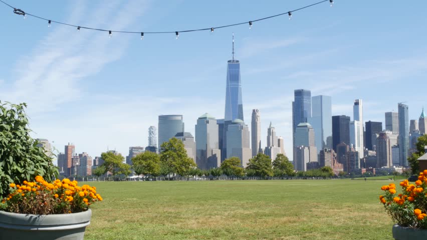 New York City Manhattan Downtown Financial District skyline, World Trade Center tower from New Jersey Liberty state park, United States. Green grass lawn, flowers and skyscraper buildings cityscape.