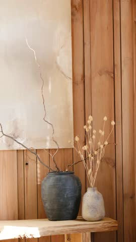 Dry branches in rustic pots against textured wooden wall, natural light