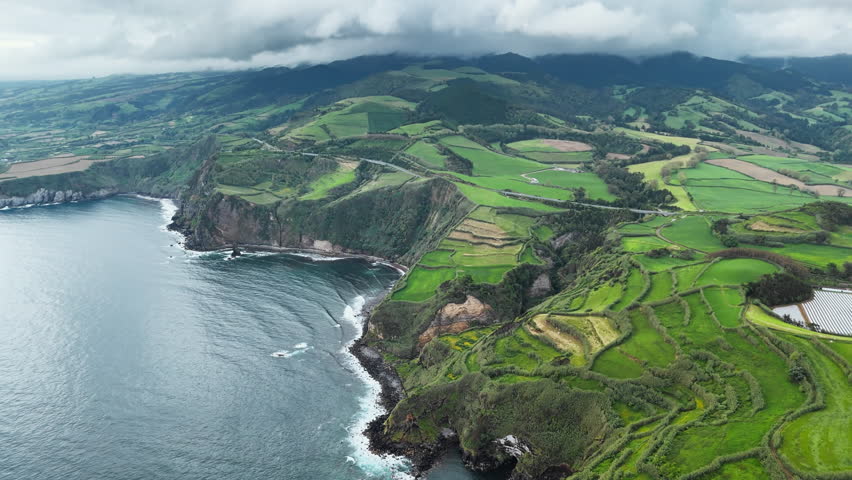 Lush green farmland on high coastal cliffs above Atlantic Ocean in Azores, Portugal. Natural island landscape, aerial view