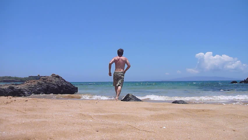 Model released man dives into ocean and returns to sandy beach on Maui, Hawaii.