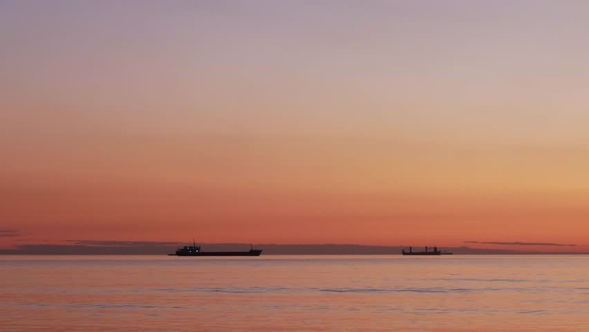 Tranquil sunset at sea with ships sailing on calm waters