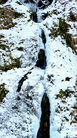 Raccolana Valley and the Fontanone di Goriuda waterfall in the snow in winter. Vertical shot.