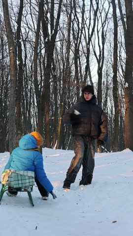 Two happy brothers playing snowball fight in snowy winter park. Joyful boys enjoying active outdoor fun, brotherhood, and screen-free childhood during winter holidays. older brother, friendship