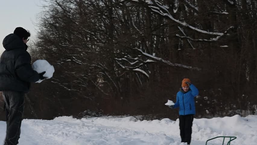 Two happy brothers playing snowball fight in snowy winter park. Joyful boys enjoying active outdoor fun, brotherhood, and screen-free childhood during winter holidays. older brother, friendship