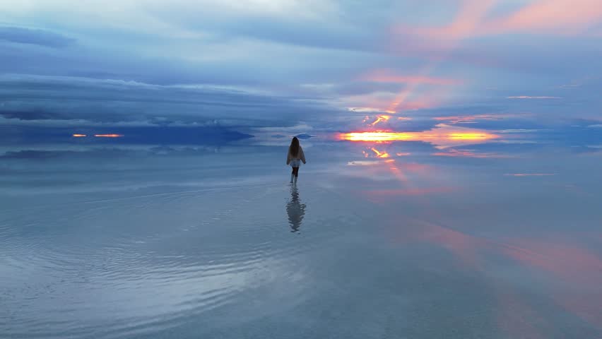 A solitary figure walks across the expansive Salar de Uyuni in Bolivia, capturing the surreal beauty of the world