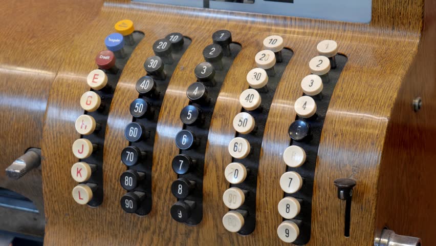 Vintage mechanical cash register keypad with worn metal buttons and inserted key, side view closeup detail, old retail shop payment and accounting concept, antique money business technology background