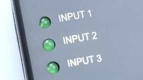 Close up panning shot of three green LED indicator lights labeled input 1 input 2 input 3 on grey audio video content switch equipment control panel, signal routing and hardware connections, no people - Powered by Shutterstock - Get 15% off with code: PIKWIZARD15
