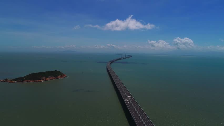 This 4K aerial time-lapse video showcases the grand Hong Kong-Zhuhai-Macao Bridge, a world-class cross-sea engineering marvel spanning the blue ocean. Capturing the bridge’s magnificent architecture against dynamic cloud movements and ocean views, it presents the stunning blend of modern engineering and coastal scenery, vividly showing the grandeur of this iconic China’s mega infrastructure project, ideal for engineering documentaries and infrastructure content.