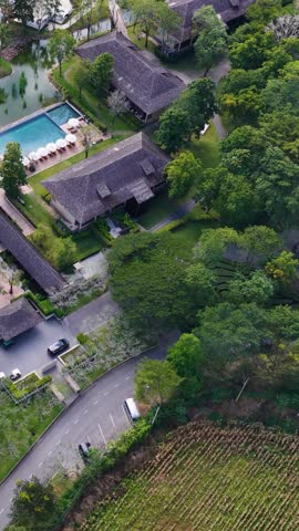 High angle drone shot reveals a tropical resort layout with pools, villas, and golf greens