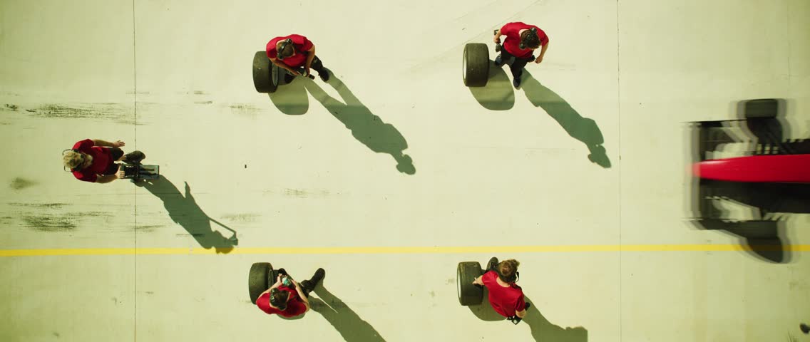 A professional formula race team works on a car in the pit, showcasing motorsport teamwork, engineering, speed, and racing action.