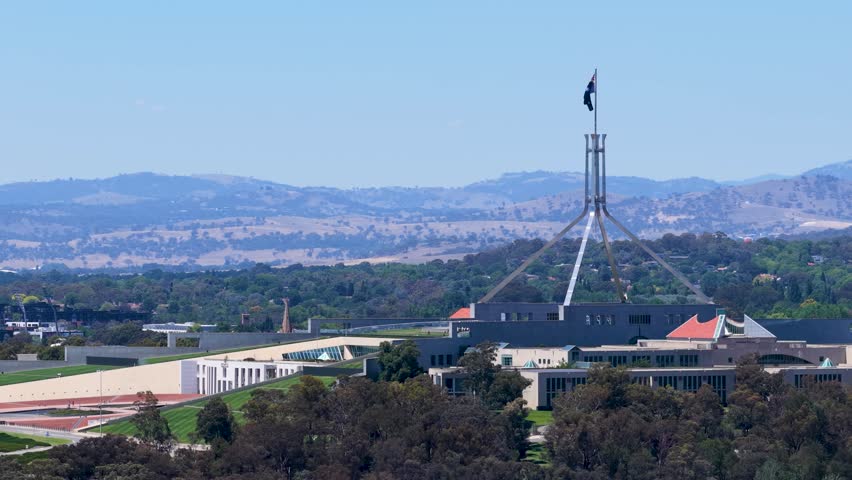 A slow horizontal pan captures the iconic Parliament House architecture under a clear blue sky