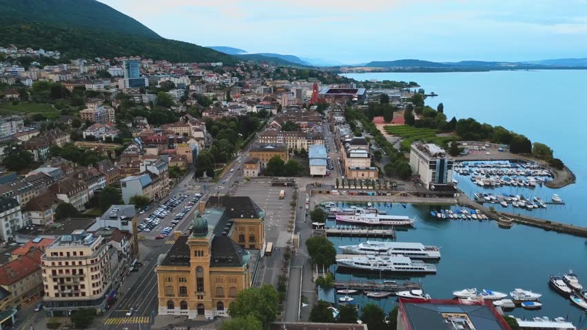 Aerial view of a coastal city harbor with boats, houses, and calm sea.
