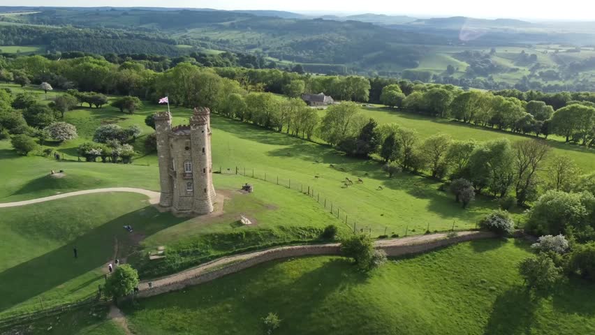 Aerial view of an old stone castle tower surrounded by green countryside.
