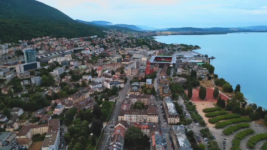 Aerial view of a coastal town with houses, marina, and blue sea.