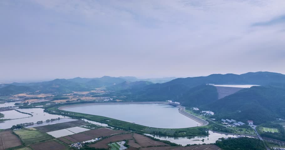Aerial time-lapse of a pumped-storage hydroelectric power station nestled among mountains, upper and lower reservoirs against a cloudy sky, Wuhu city, Anhui province, China