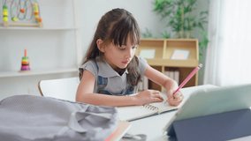 Caucasian young kid learning online class with teacher in cozy house. Adorable child student using digital tablet doing homework and study from school tutor by virtual remote in living room at home. - Powered by Shutterstock - Get 15% off with code: PIKWIZARD15