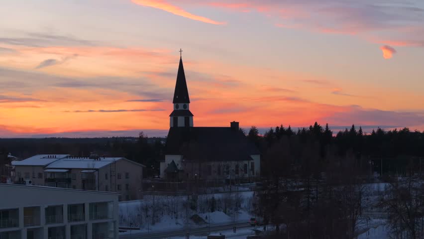 4K cinematic drone footage of Rovaniemi Church (Rovaniemen kirkko) in Finland during golden hour at the winter solstice, showcasing the Nordic church architecture surrounded by snow_72
