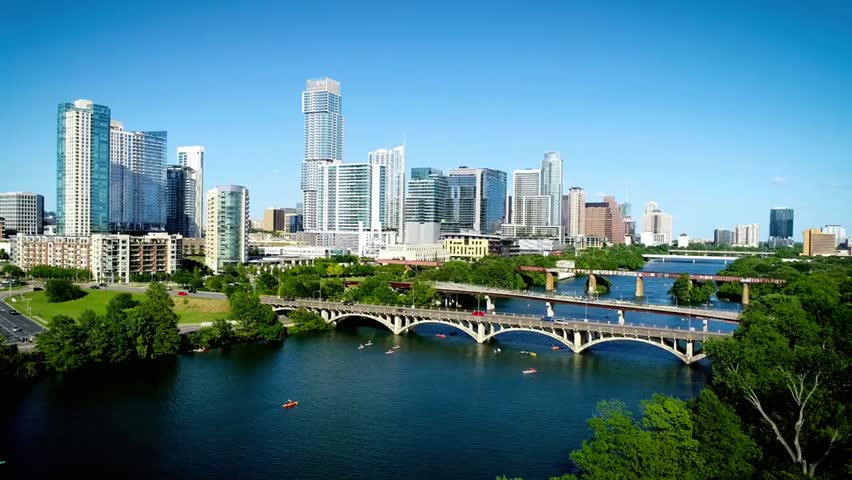 Aerial view of Austin, Texas skyline with bridges spanning the Colorado River, showcasing urban architecture, riverfront, and cityscape beauty.
