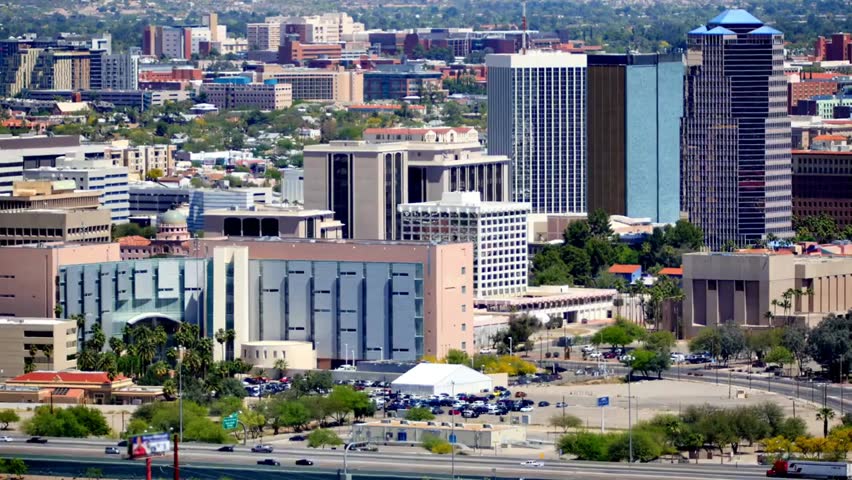 Panoramic view of Tucson, Arizona cityscape during daytime, showcasing urban buildings, streets, and the surrounding desert landscape.
