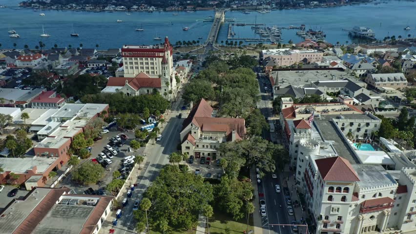 St. Augustine downtown area with historic architecture, tree-lined streets, and a waterfront marina featuring docks and sailboats, connected by bridges over the water in Florida.