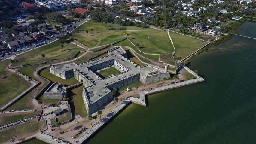 Historic Castillo de San Marcos fort in St Augustine, Florida, with stone walls and moat, located on the waterfront adjacent to urban neighborhoods and green spaces.
