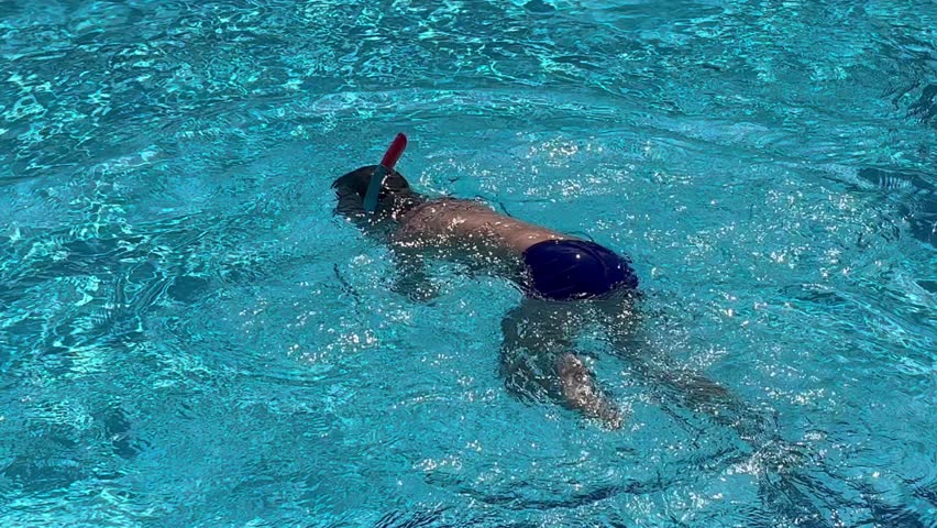 A boy of 8-9 years old swims in the pool, dives under the water with a mask, dives, swims out. Summer Christmas vacation by the pool. Swimming for children.