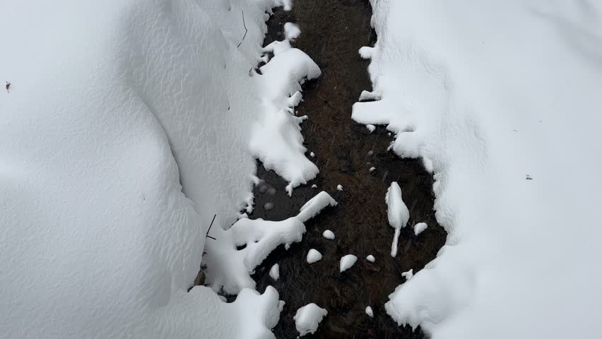 Winter creek surrounded by large snowdrifts