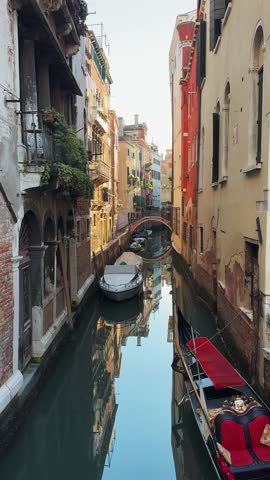 Old venetian architecture on the canal with bridge in Venice, Italy. Gondolas on the canal. Beautiful autumn cityscape. Famous travel destination. Vertical video
