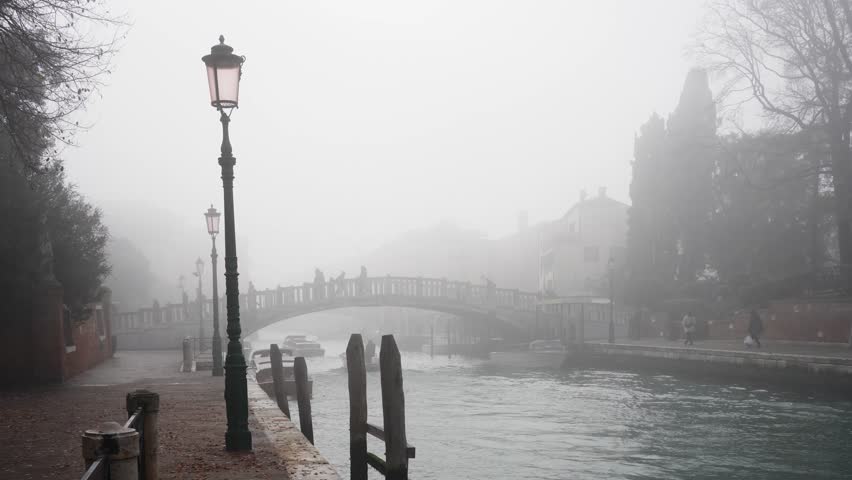 Foggy morning in Venice, Italy. Old venetian architecture and bridge on the canal. People walking on the bridge. Winter cityscape. Famous travel destination
