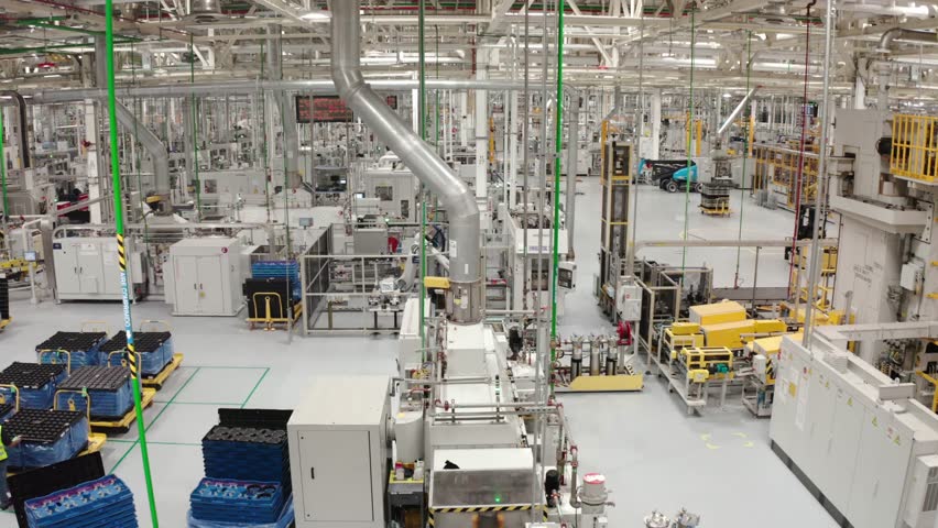 Wide view of a modern automated factory floor with machinery, conveyors, and overhead piping in a clean industrial facility, showcasing smart manufacturing and robotics.