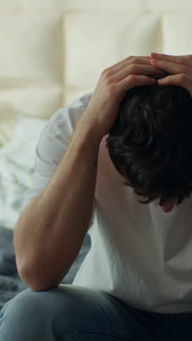 Worried tired Caucasian man sitting bed home holding head stressed male in bedroom exhausted anxious guy headache pain problems crisis trouble frustration failure sadness stress mental fatigue indoors