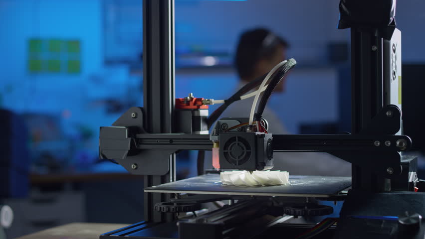 Professional engineer adjusts settings of a 3D printer while producing prototypes in a modern laboratory focusing on additive manufacturing.