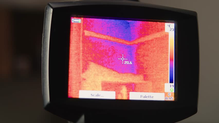 Man technician uses a thermal camera scope to detect heat loss. Engineer using imaging camera diagnosis checking space and people.