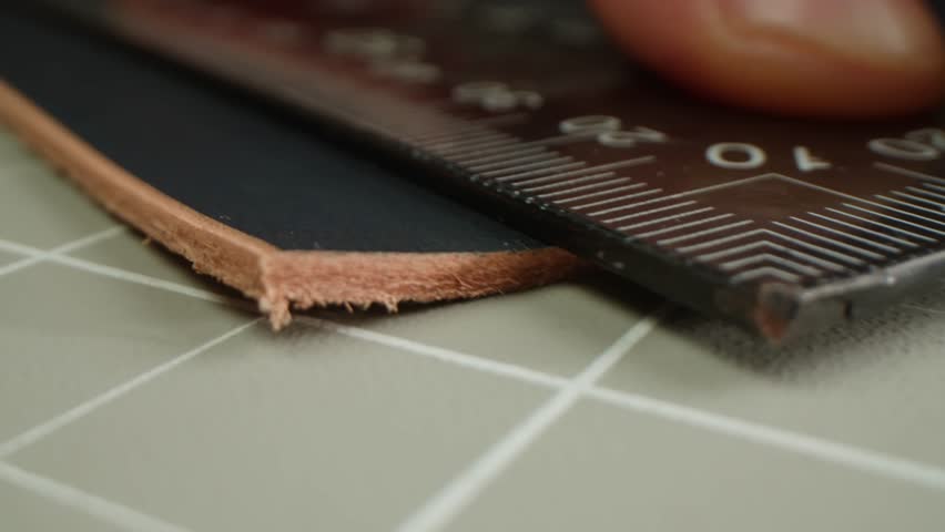 Man tailor repairing belt, artificial leather close-up. Craftsman making accessories made of genuine animal leather at workplace table. Professional atelier.