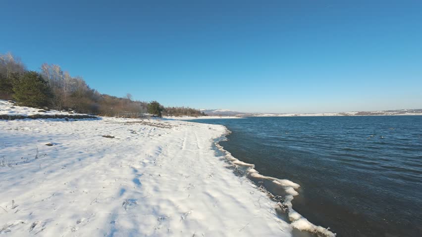Flight over frozen lake shore