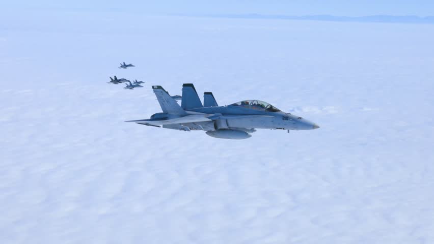 Military fighter jets flying in high altitude formation above thick clouds with mountains clearly visible below.