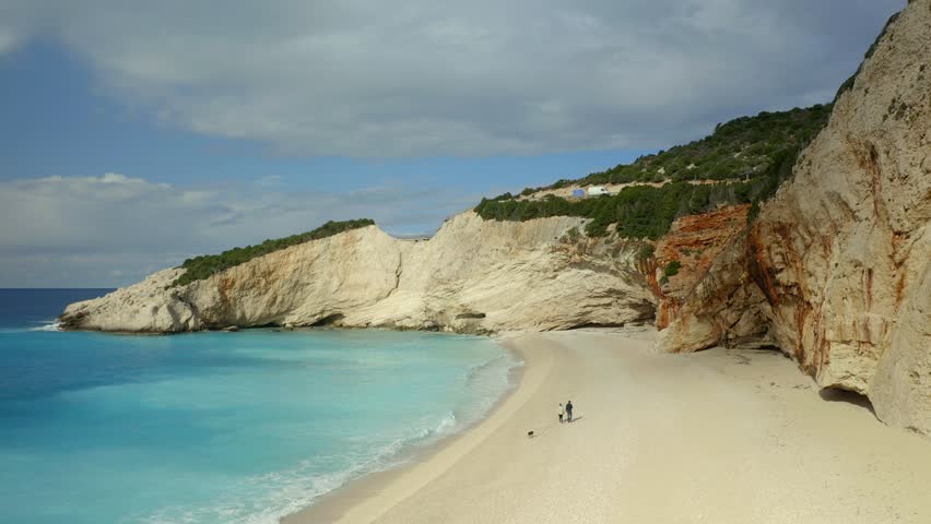 Drone aerial view of couple walking on iconic Porto Katsiki beach in Lefkada island with turquoise water, in Greece