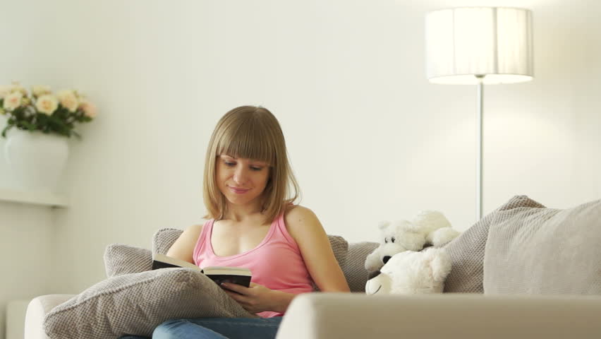 Young woman relaxing in the living room and reading a book
