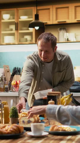 Vertical Video Father packing school lunch for his pre-teen daughter and preparing backpack, family members enjoying breakfast together during cozy morning in the kitchen. Meal prep school bag. Camera