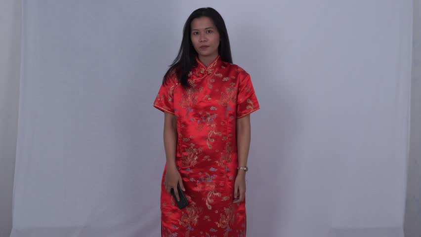 Asian woman in red cheongsam smiling and talking to someone on the phone