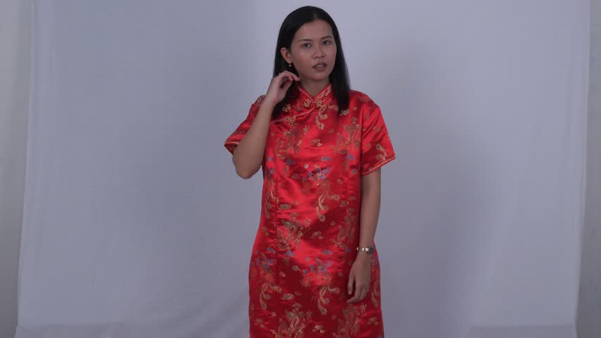 Asian woman in red Cheongsam is fixing her hair