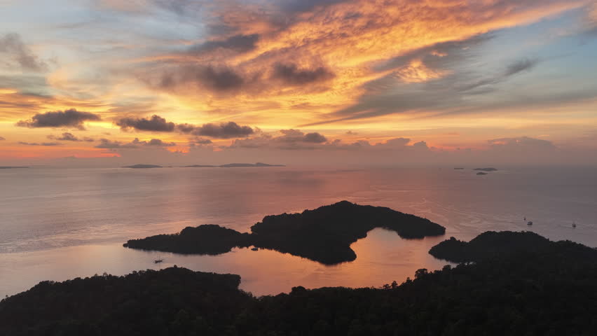 A beautiful sunset silhouettes the islands of Gam and Yangeffo in Raja Ampat, Indonesia. This area is known as the heart of the Coral Triangle due to its incredible marine biodiversity.