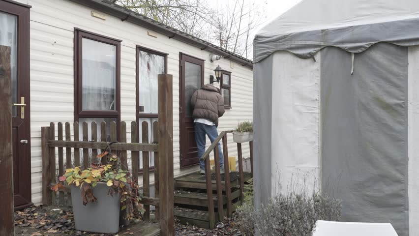 Young man trying to open the wooden bulgalow door during daytime.